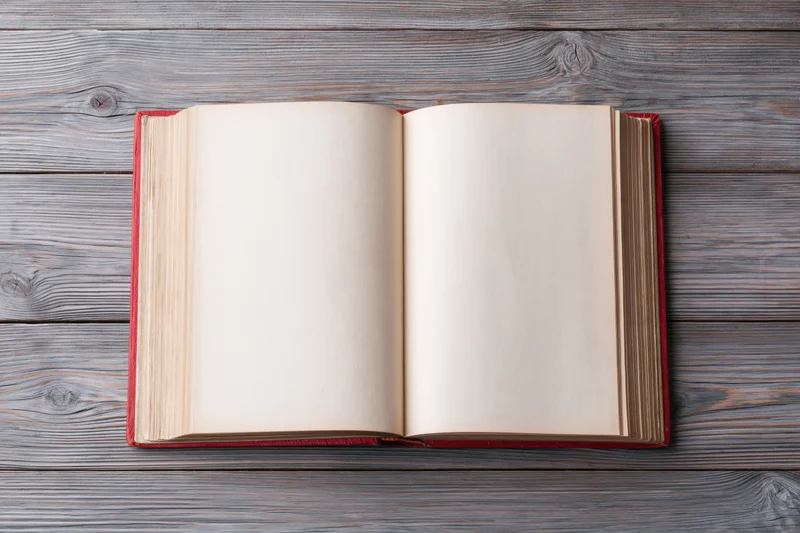 Open hardcover book with blank pages lying flat on a wooden table