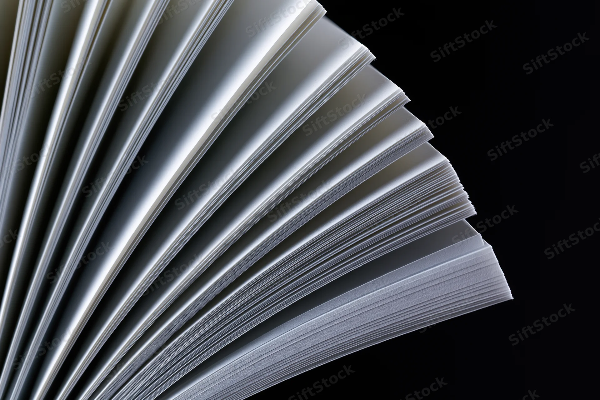 Open book with pages fanned in wide arc against black background