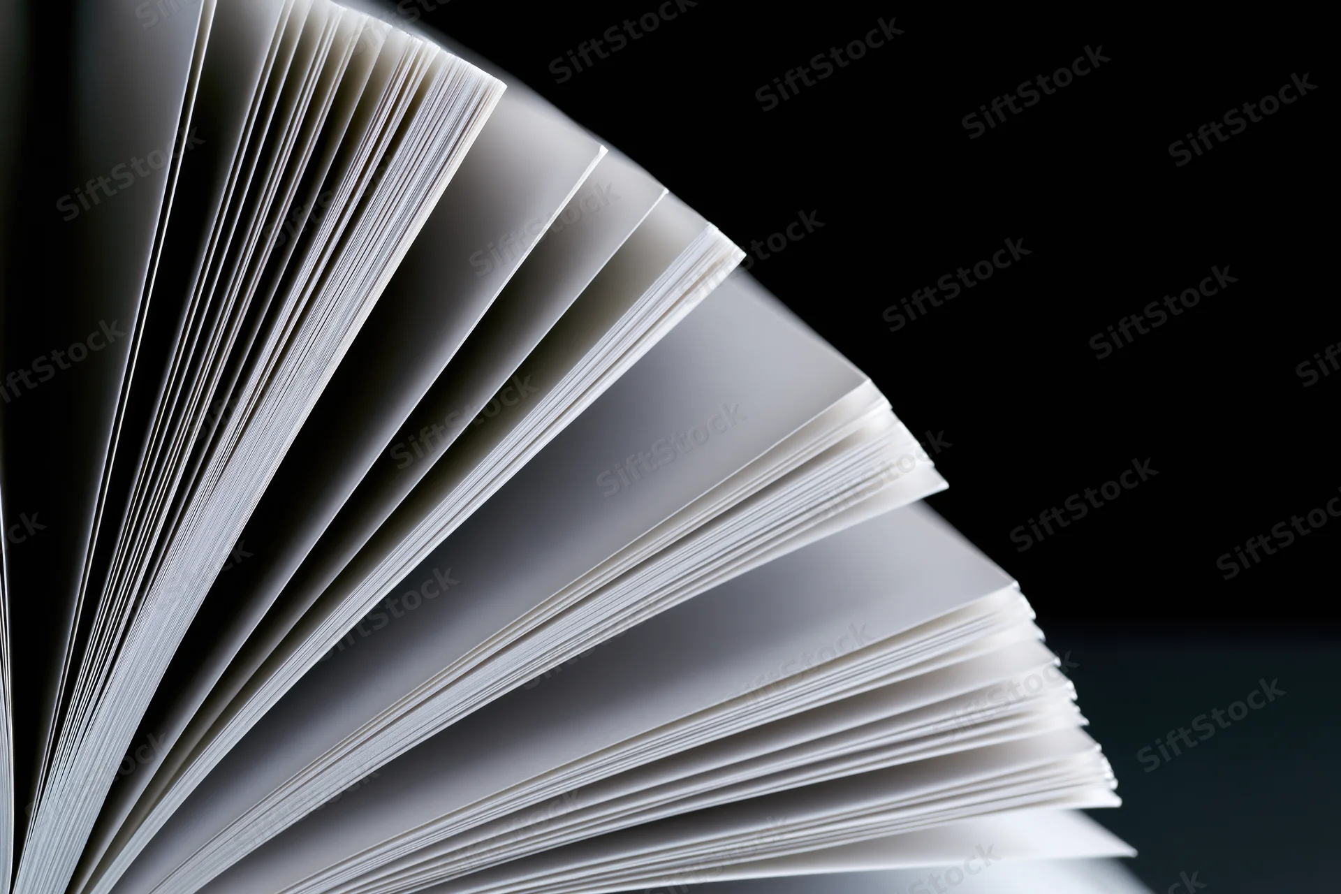 Open book with pages fanned in wide arc against black background