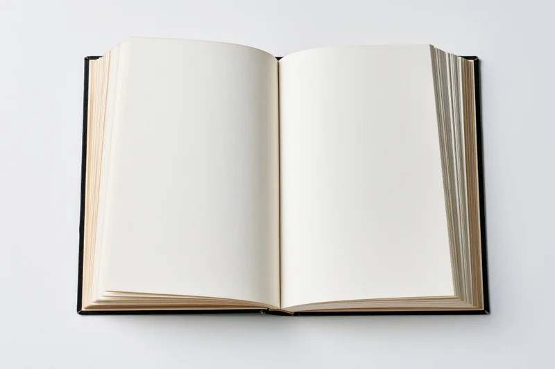 Open hardcover book with blank cream pages lying flat spread on white background