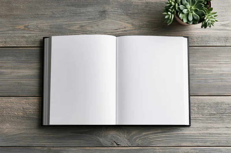 Open hardcover book with blank white pages lying flat on wooden table with succulent plant nearby