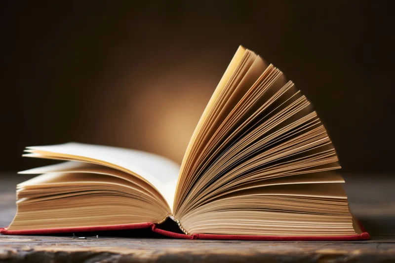 Open hardcover book with fanned pages resting on a worn wooden surface