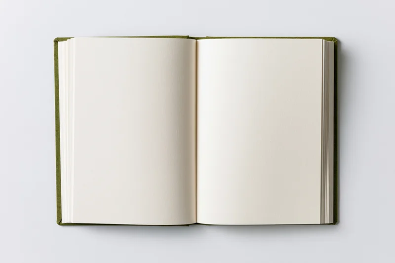 Open hardcover notebook lying flat with blank white pages on a white surface