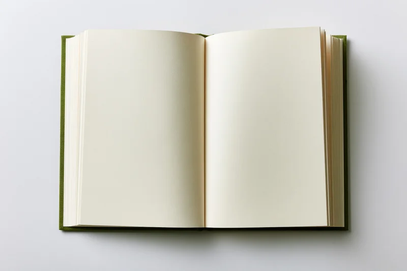 Open hardcover notebook lying flat with blank pages on white surface