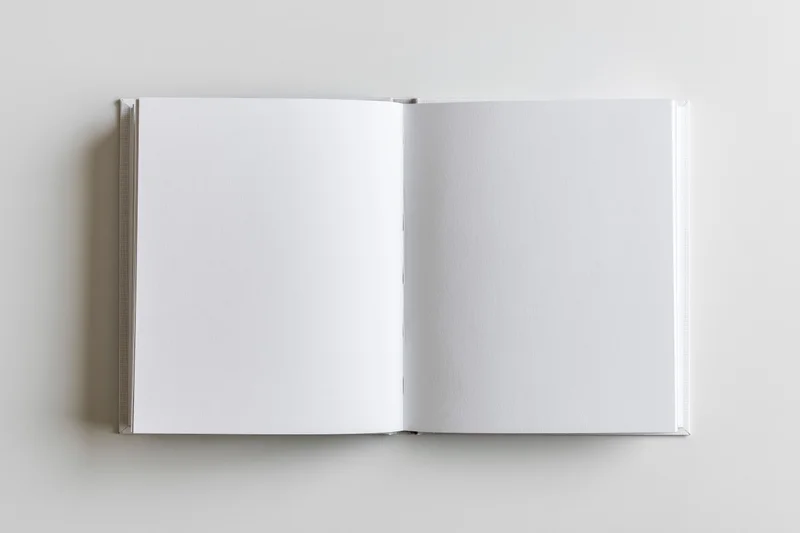 Open square hardcover book lying flat with blank white pages
