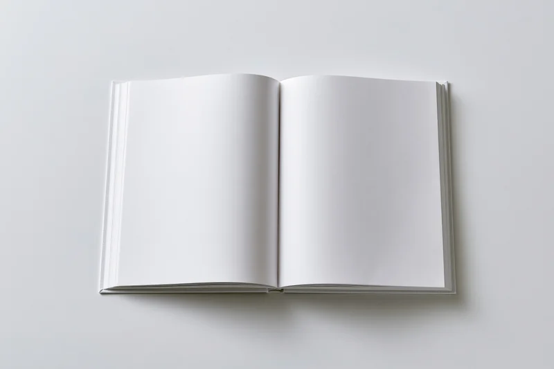 Open hardcover book with blank white pages lying flat on white surface
