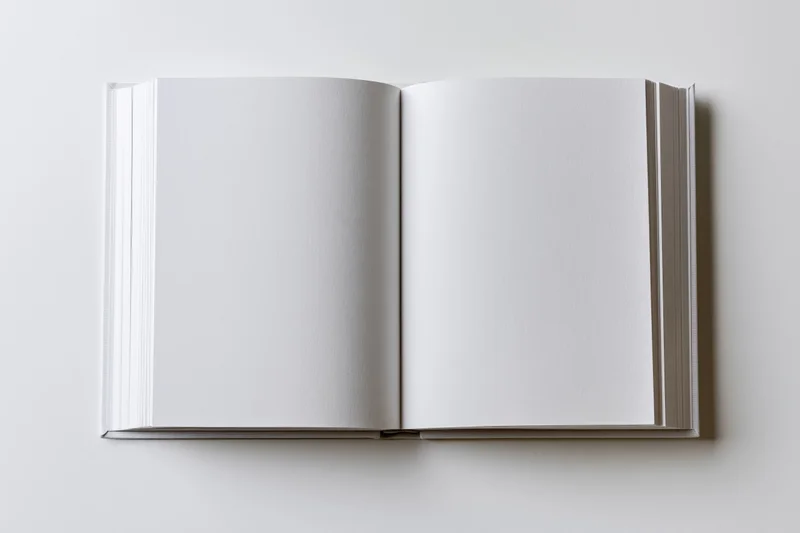Open hardcover book with blank white pages on plain white surface