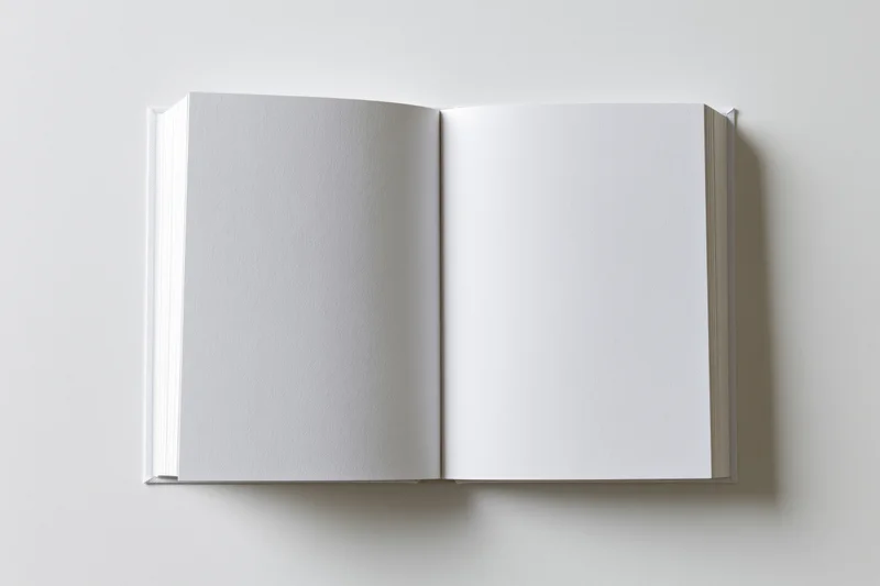 Open hardcover book with blank white pages on plain surface
