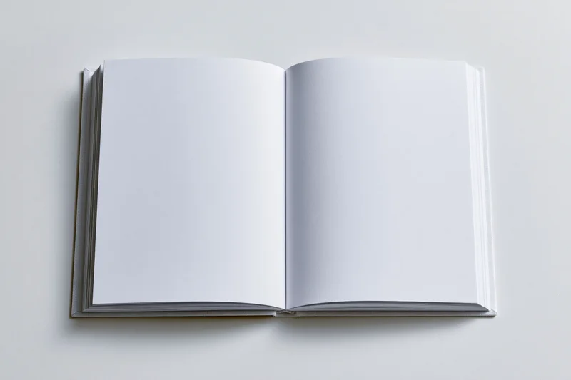 Open hardcover book with blank white pages on a plain surface