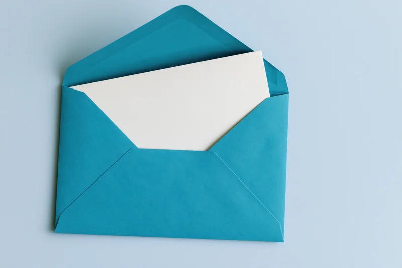Open teal envelope with blank white card inside on light blue surface