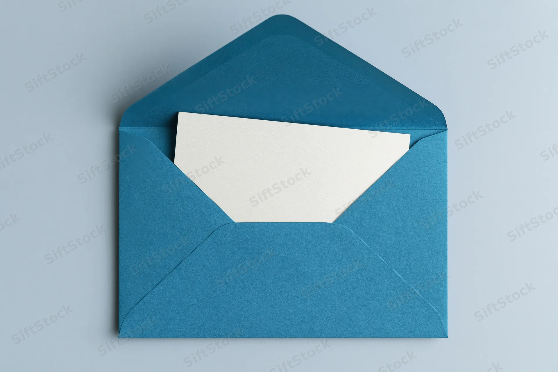 Open teal envelope with blank white card inside on light gray surface
