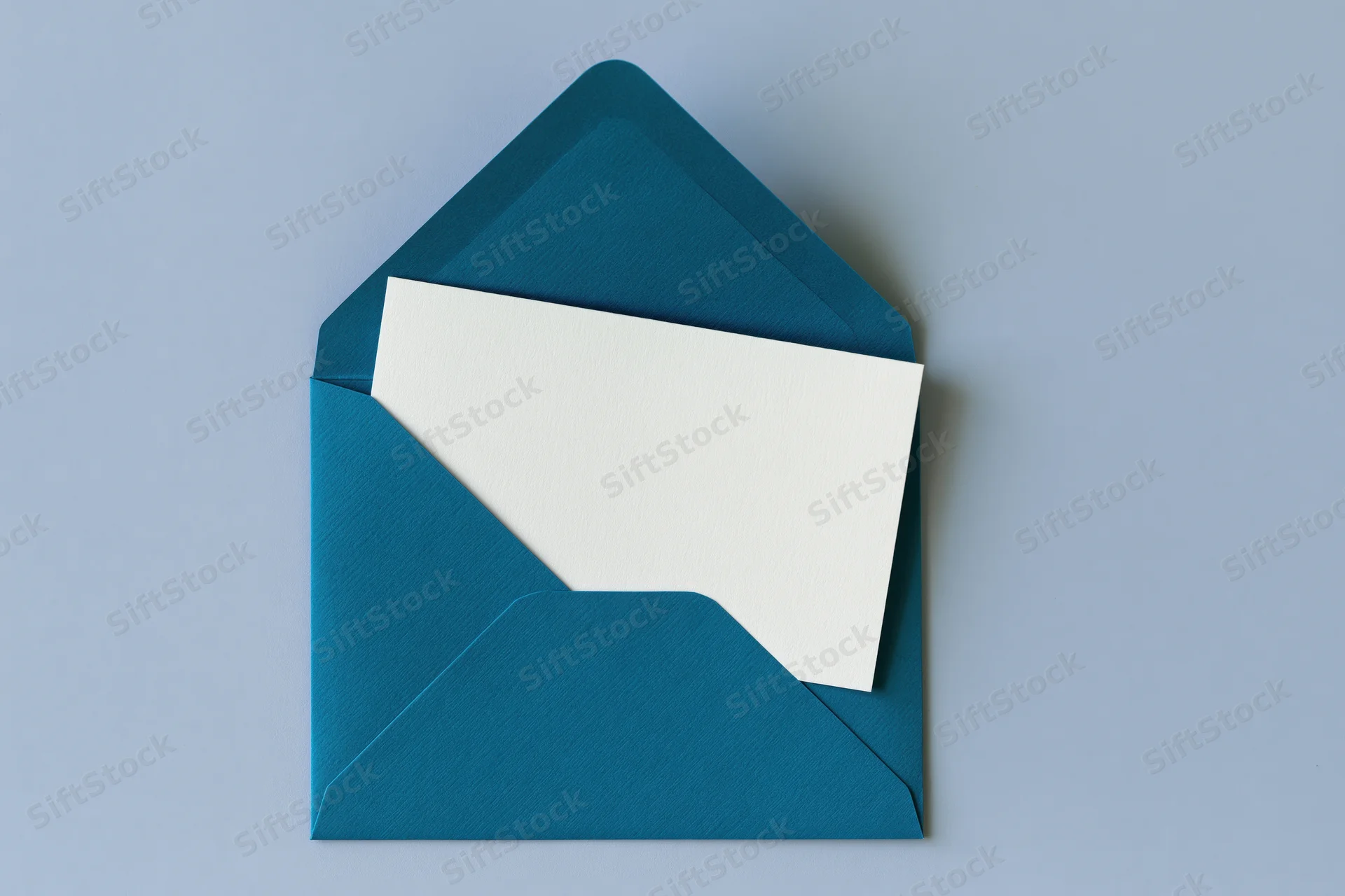 Open teal envelope with blank white card inside on light blue surface