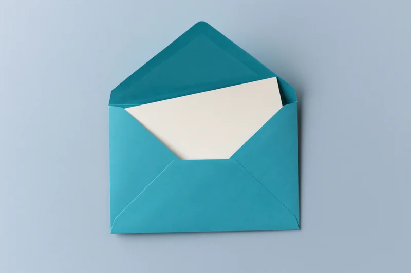 Open teal envelope with blank white card inside on light blue surface