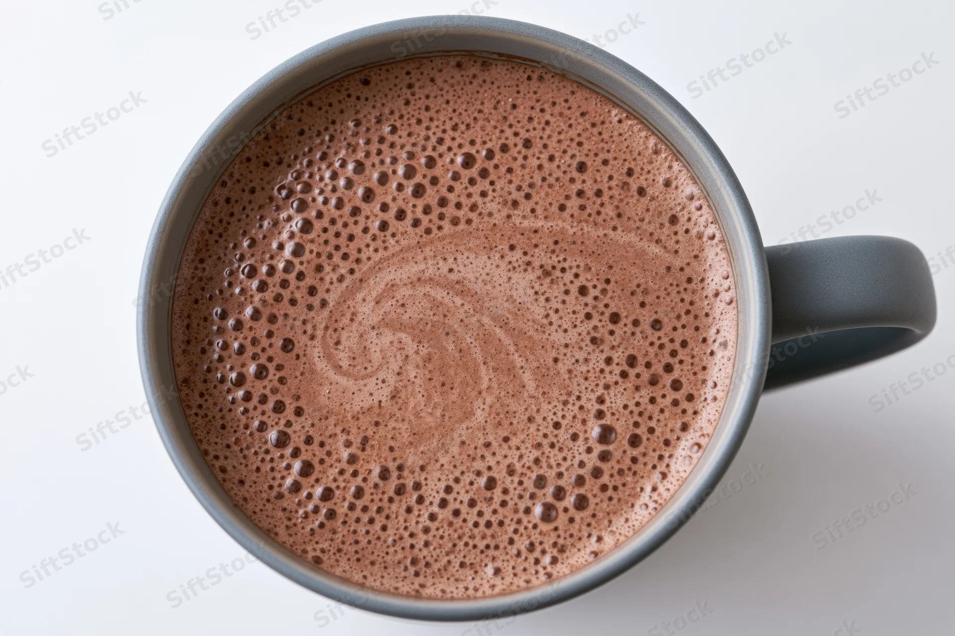 Overhead view of a grey ceramic mug filled with frothy hot chocolate on a white surface