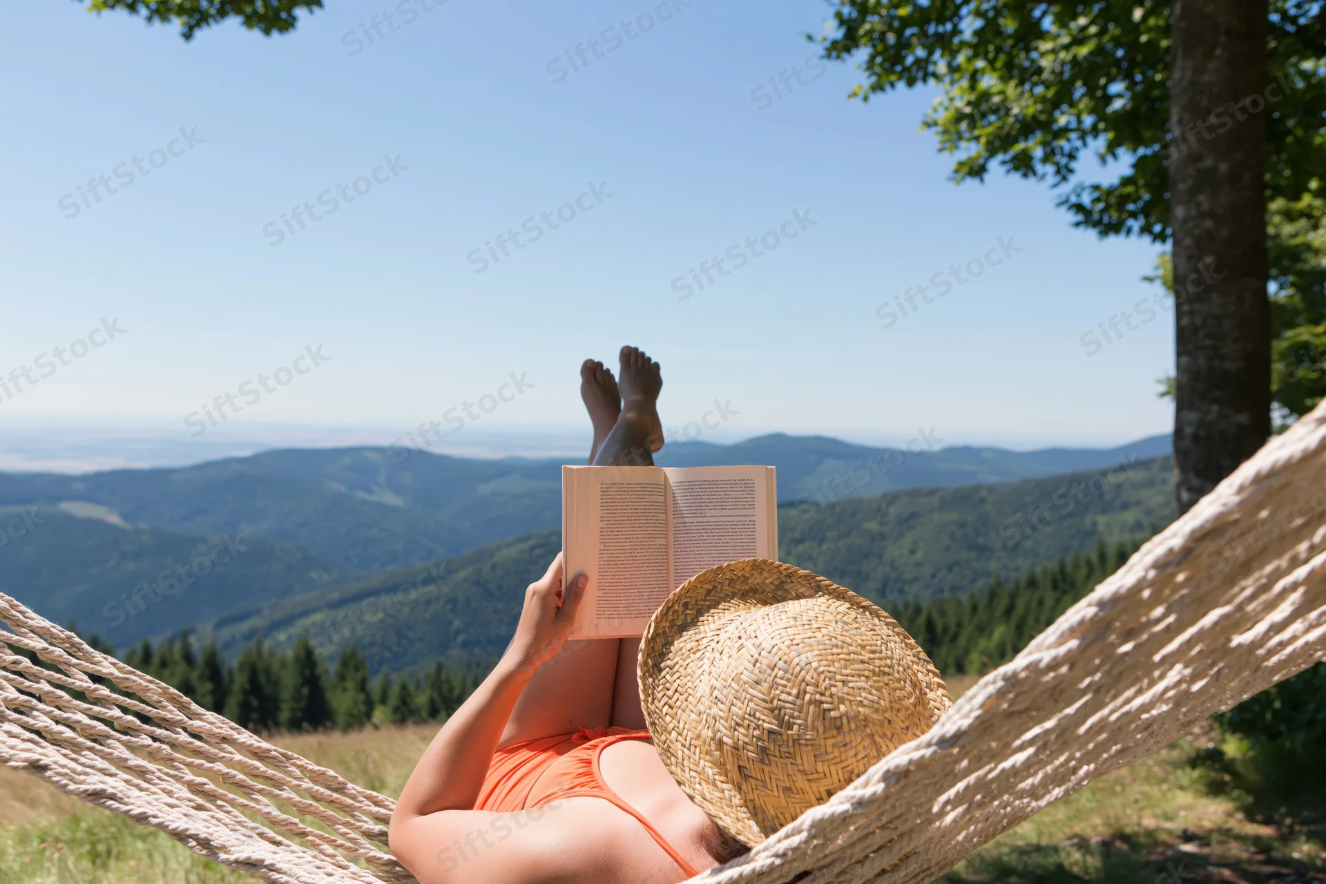 Woman lying in a rope hammock reading a book with legs raised, overlooking a mountainous landscape