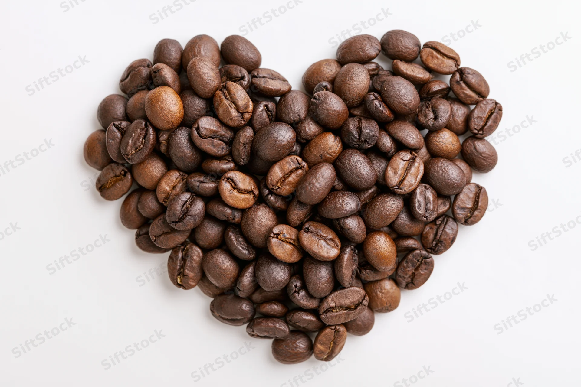 Roasted coffee beans arranged in heart shape on white background