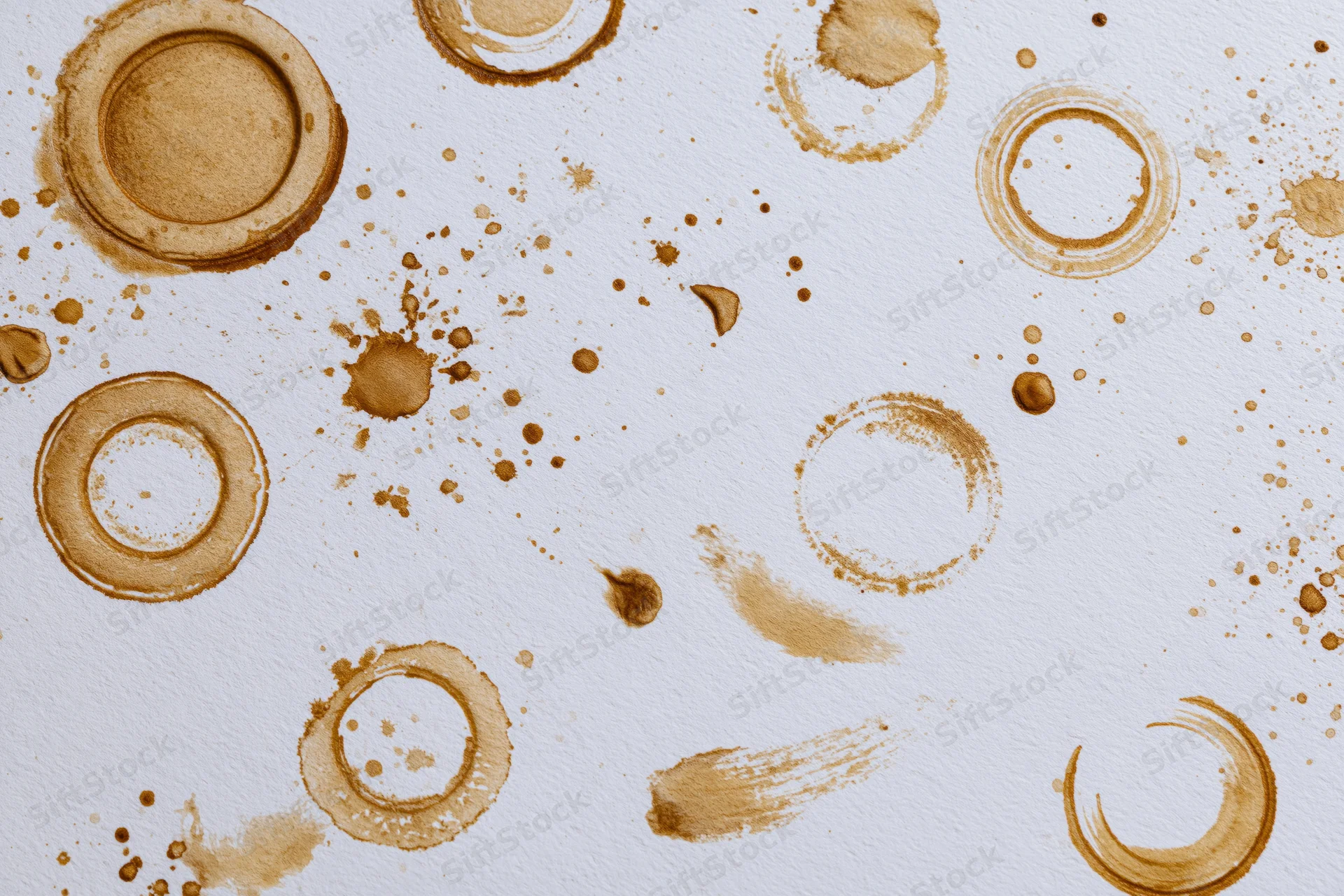 Coffee stains and ring marks scattered across white paper surface