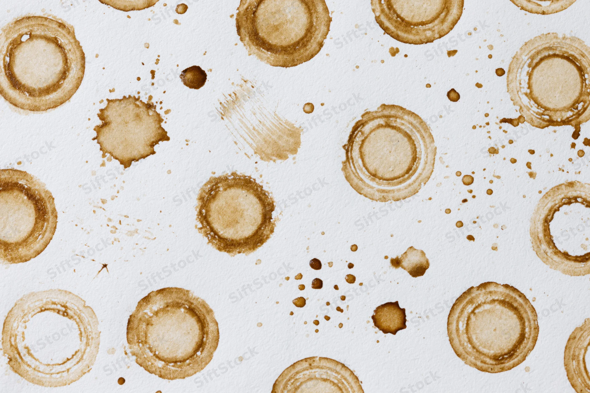 Coffee ring stains and splatters scattered across white paper surface