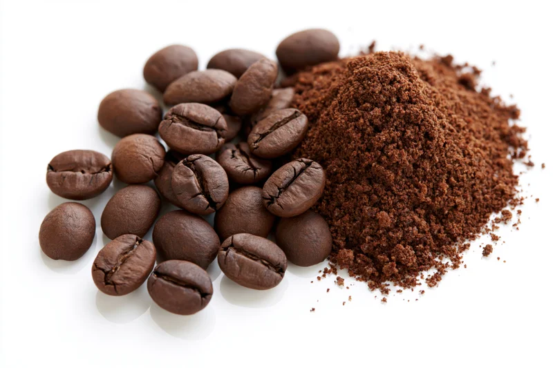 Whole roasted coffee beans and ground coffee piled together on white background