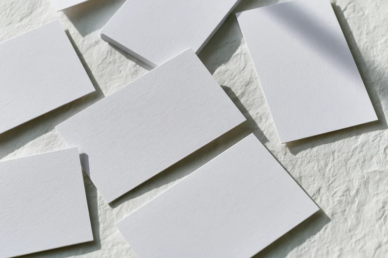 Blank white business cards scattered at slight angles on textured surface