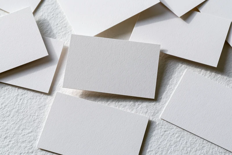 Blank white business cards scattered on textured surface