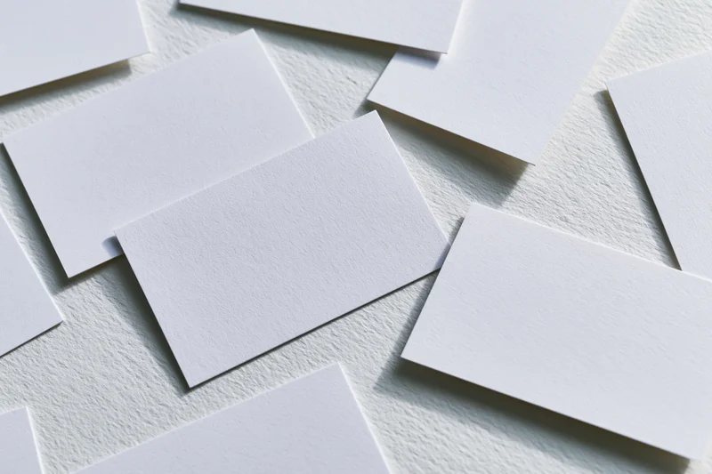 Blank white business cards scattered on textured surface in flat lay arrangement