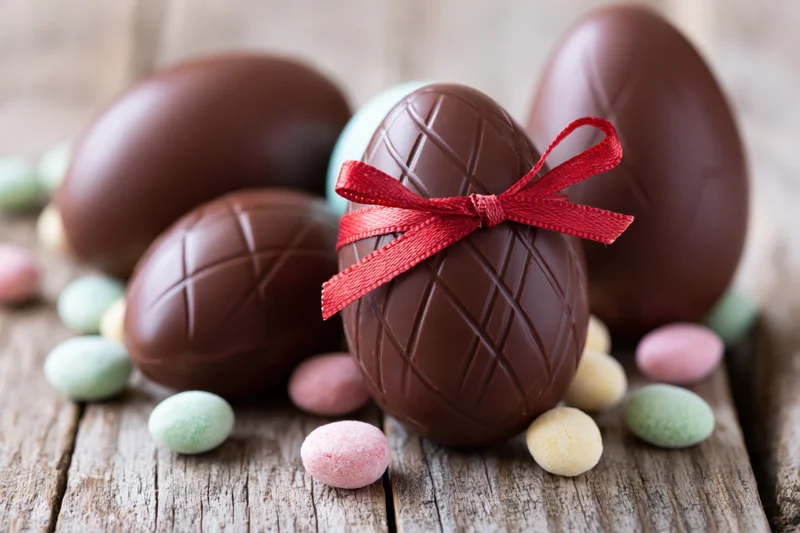 Chocolate easter eggs with red ribbon arranged on rustic wooden table