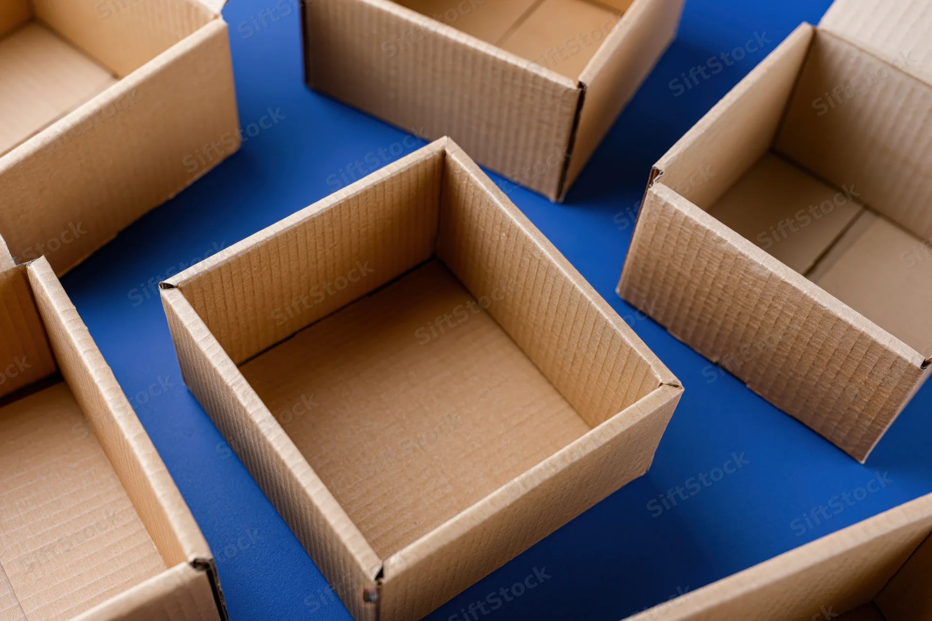 Open empty cardboard shipping boxes scattered on a blue surface