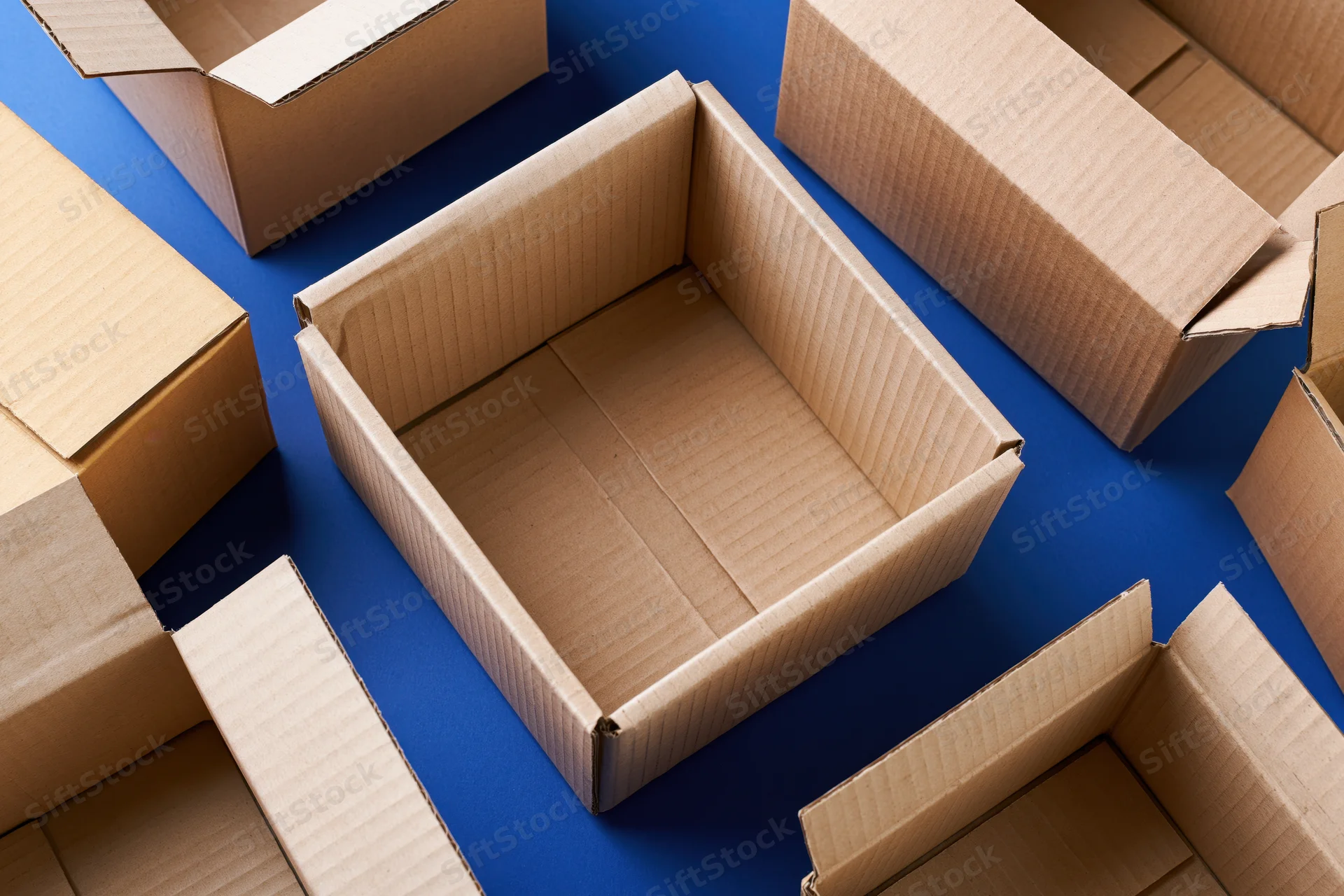 Open empty cardboard shipping boxes scattered on blue surface viewed from above