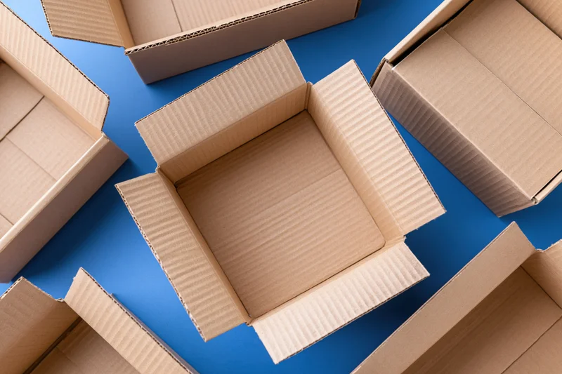 Open empty cardboard shipping boxes scattered on blue surface viewed from above