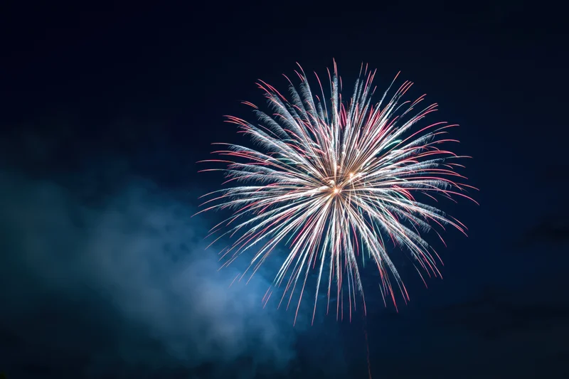 Large firework burst exploding in the night sky with smoke and colorful sparks