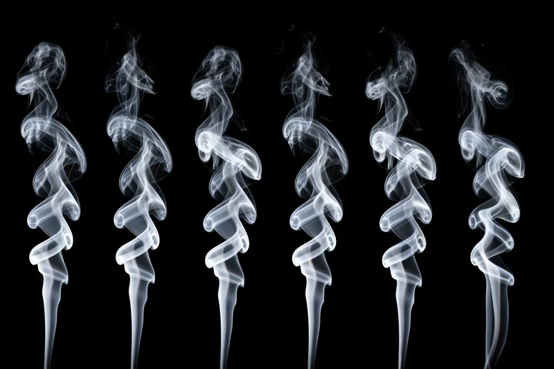 Six white smoke plumes rising in swirling patterns against a black background