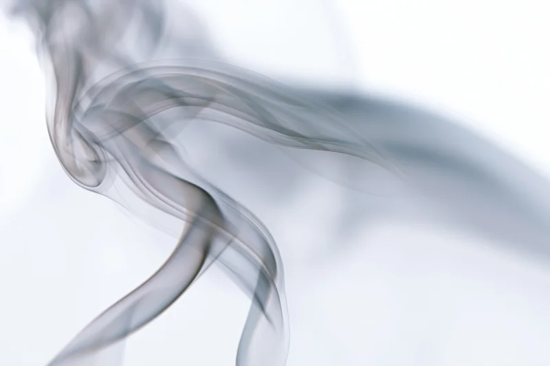 Thin wisp of smoke curling upward against a white background