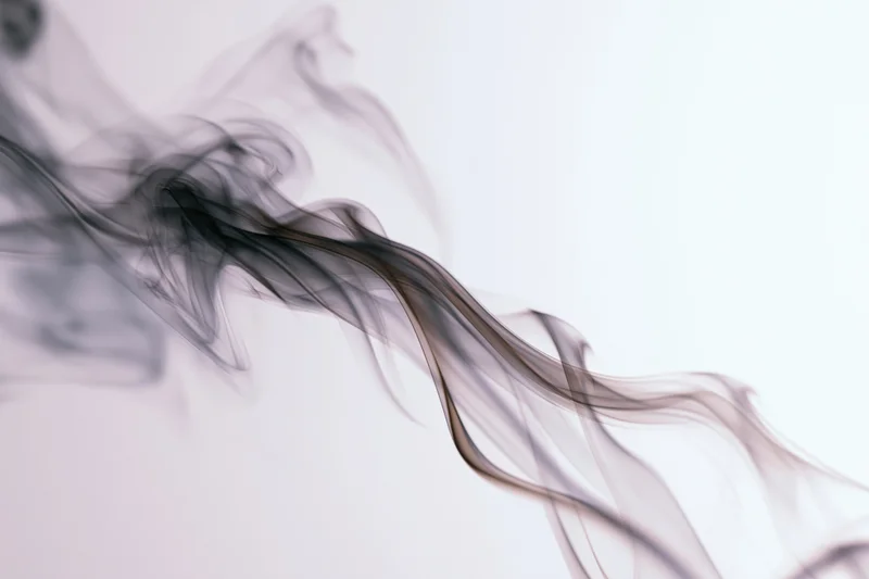 Dark smoke wisps curling upward against a white background