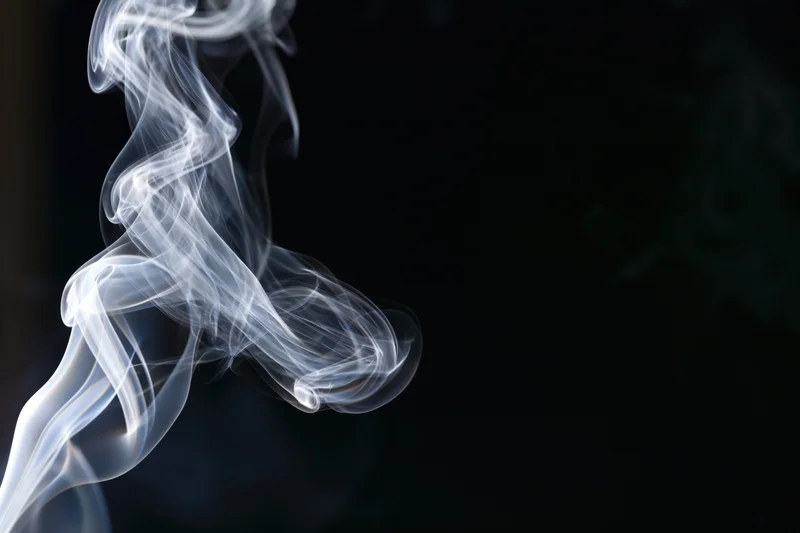 White smoke curling upward against a dark background
