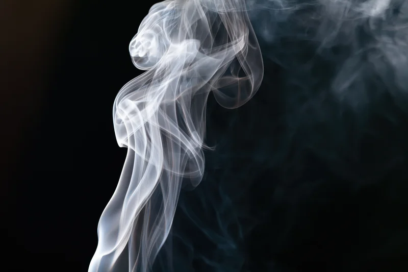 White smoke curling upward against a dark background