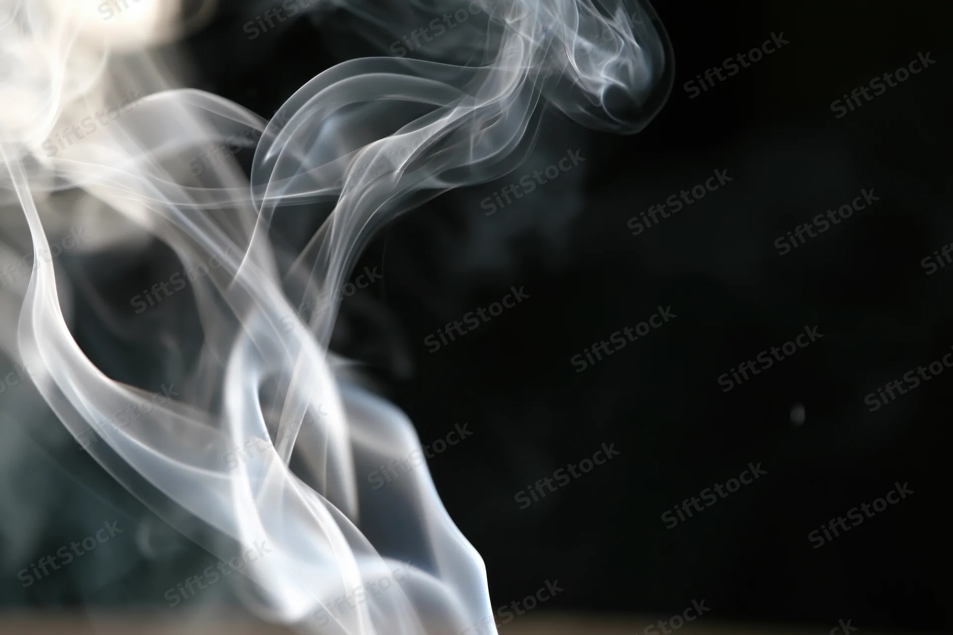 Thin white smoke curling upward against a dark background