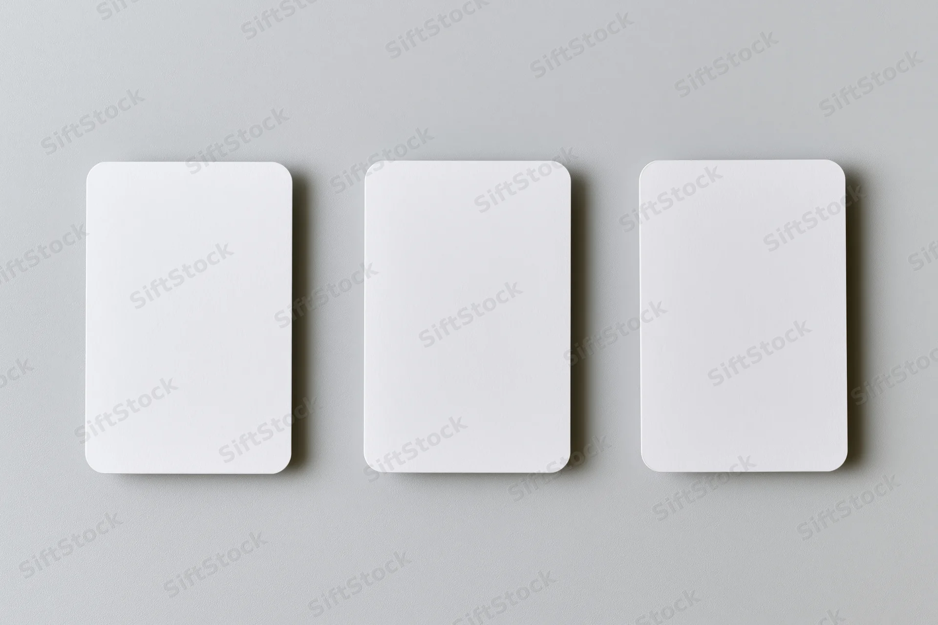 Three blank white cards with rounded corners arranged horizontally on a gray surface