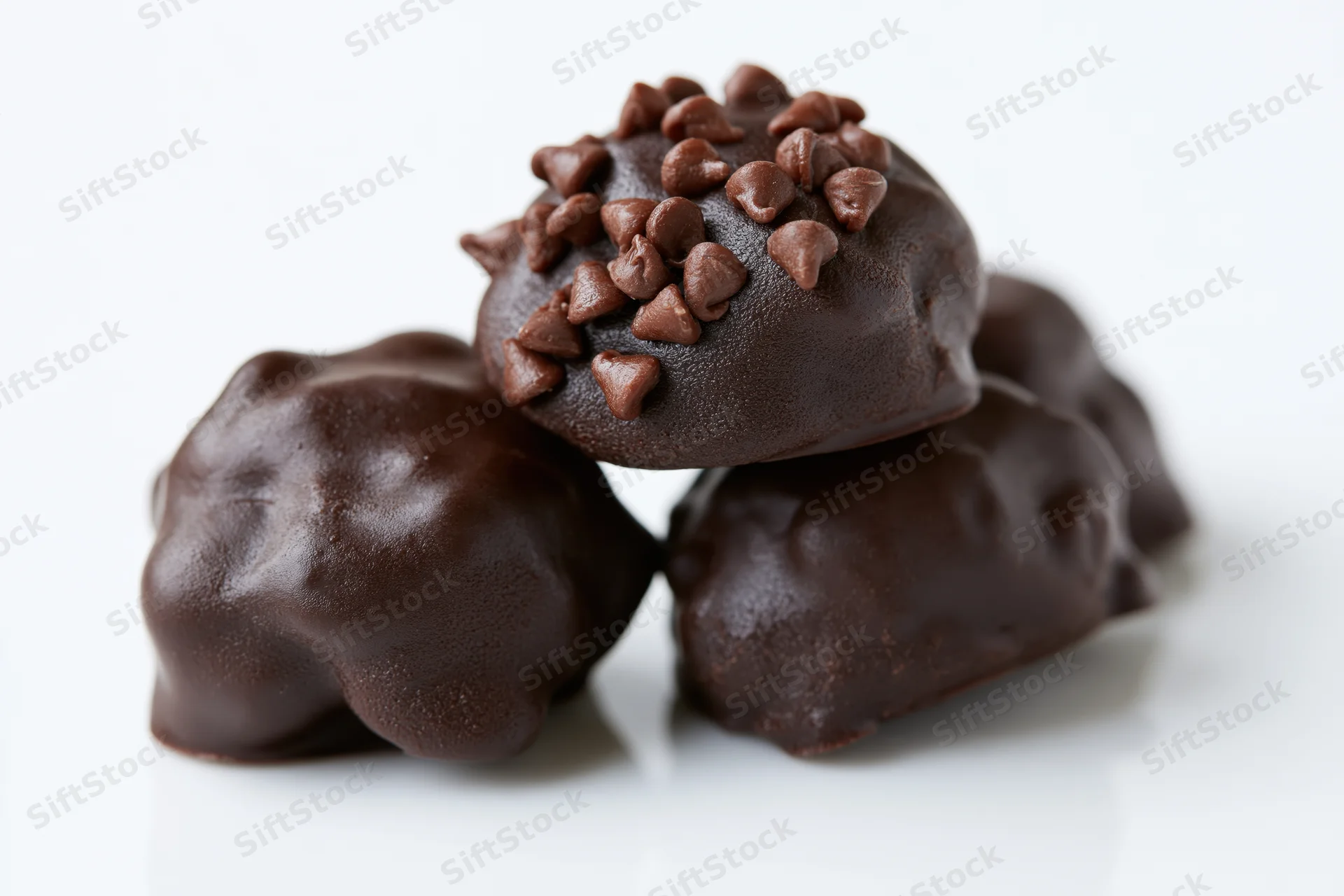Dark chocolate-coated candies clustered together on white background