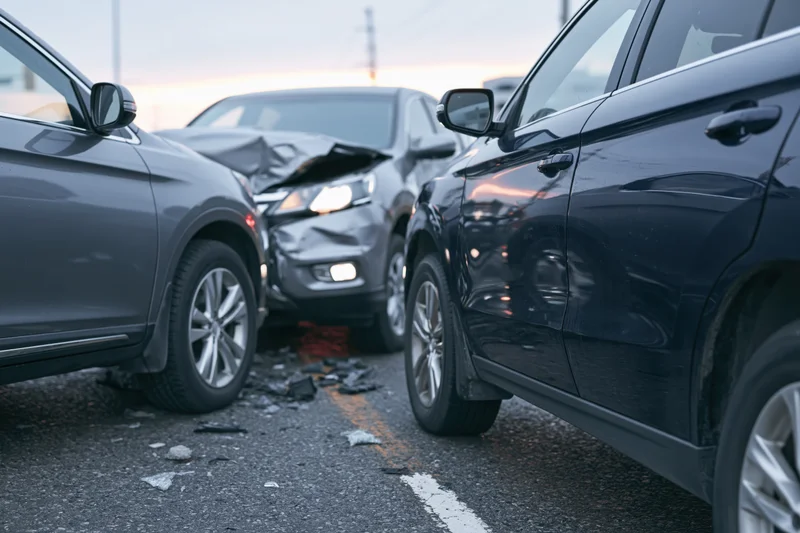 Two suvs involved in a front-end collision on an urban road with visible damage and debris on the asphalt