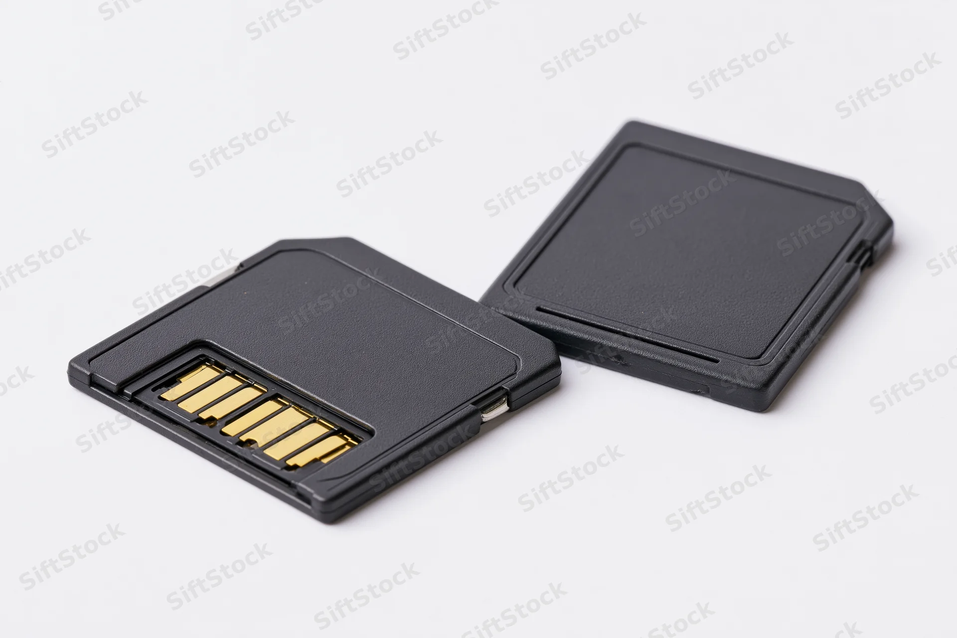 Two black sd memory cards side by side on white surface showing gold connectors