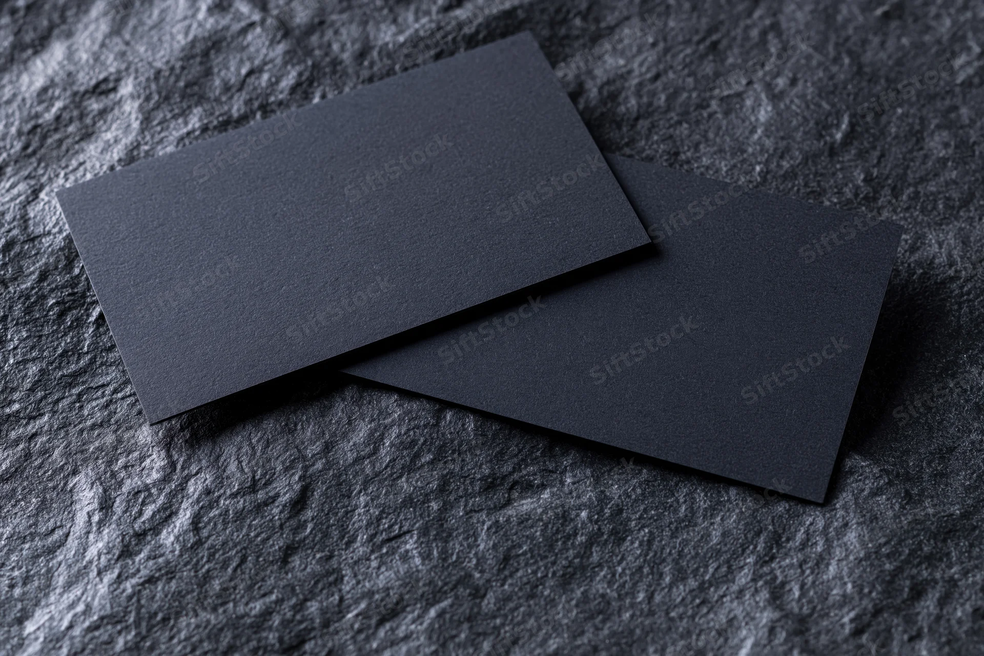 Two blank dark navy business cards overlapping on a textured stone surface