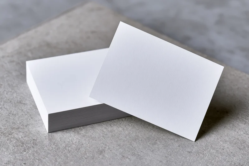 Blank white business cards arranged on a grey concrete surface