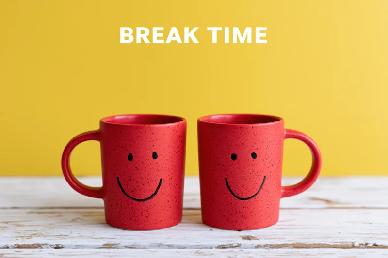 Two red ceramic coffee mugs with smiley faces on a wooden table against a yellow background