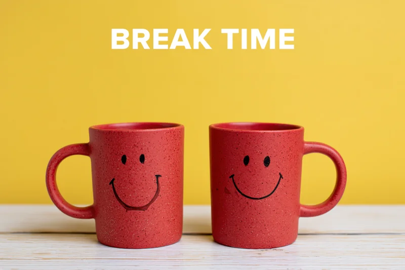 Two red ceramic coffee mugs with hand-drawn smiley faces on a white wooden table against a yellow background with text break time