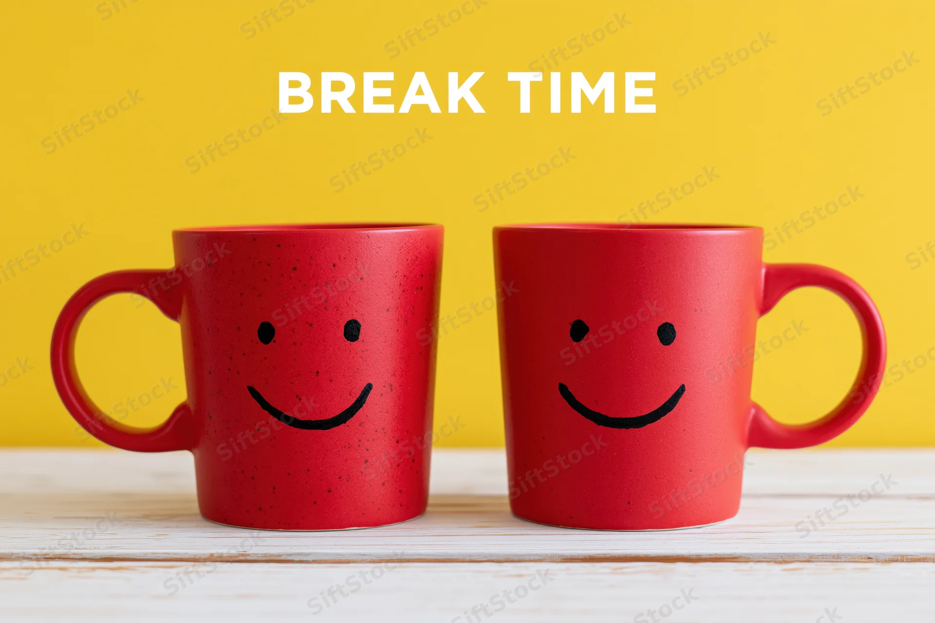 Two red ceramic coffee mugs with smiley faces on a white wooden table against a yellow background