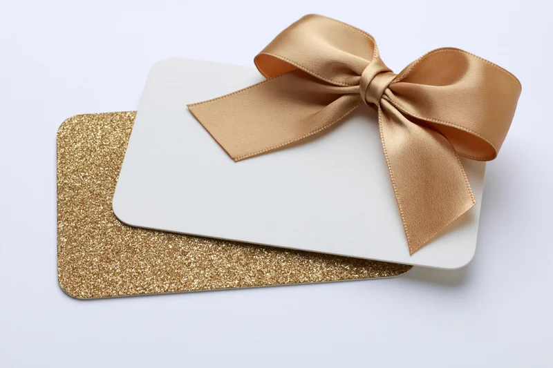 Two stacked gift cards with a gold satin bow on a white background