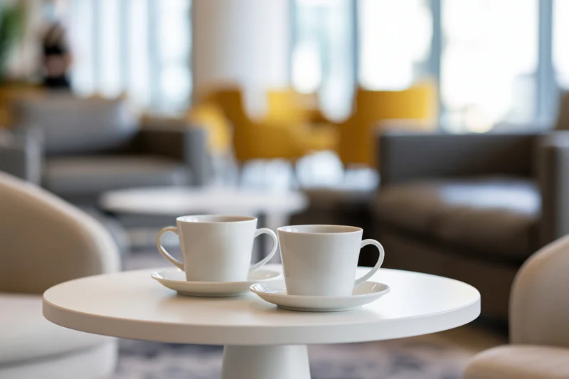 Two white ceramic coffee cups on saucers on a round table in a modern lounge setting