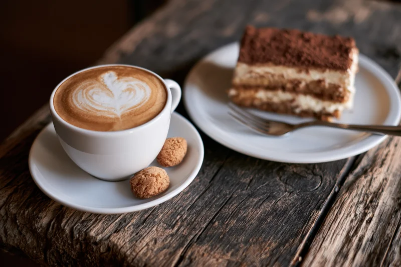 Cappuccino with heart-shaped latte art and tiramisu on a rustic wooden table