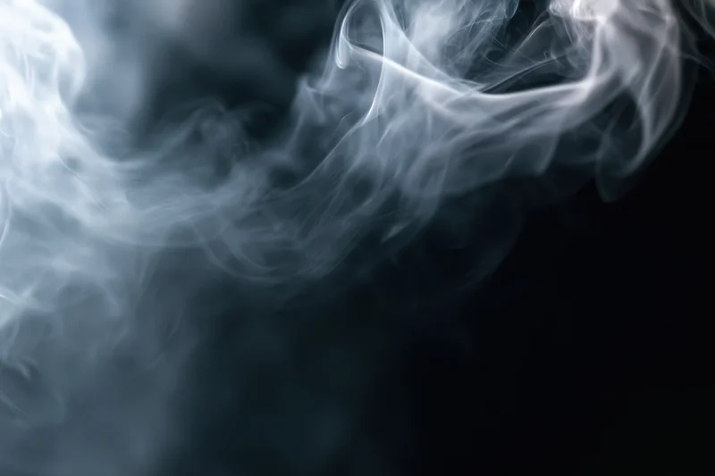 White smoke swirling upward against a dark background
